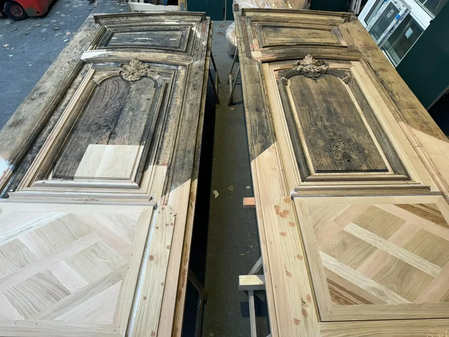 Deux portes en bois finement sculptées et un panneau inférieur de style parquet, dans un atelier. à Paris — Menuisier — par Entreprise Francois